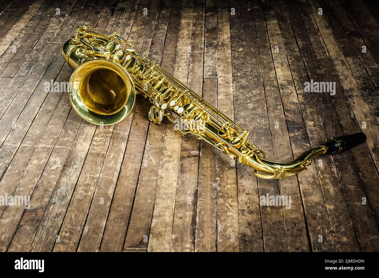 Lo strumento musicale giallo sassofono si trova su un pavimento in legno Foto Stock