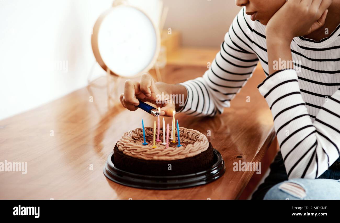 Tutti hanno dimenticato il mio compleanno. Una donna che illumina le candele su una torta di compleanno a casa e sembra triste. Foto Stock