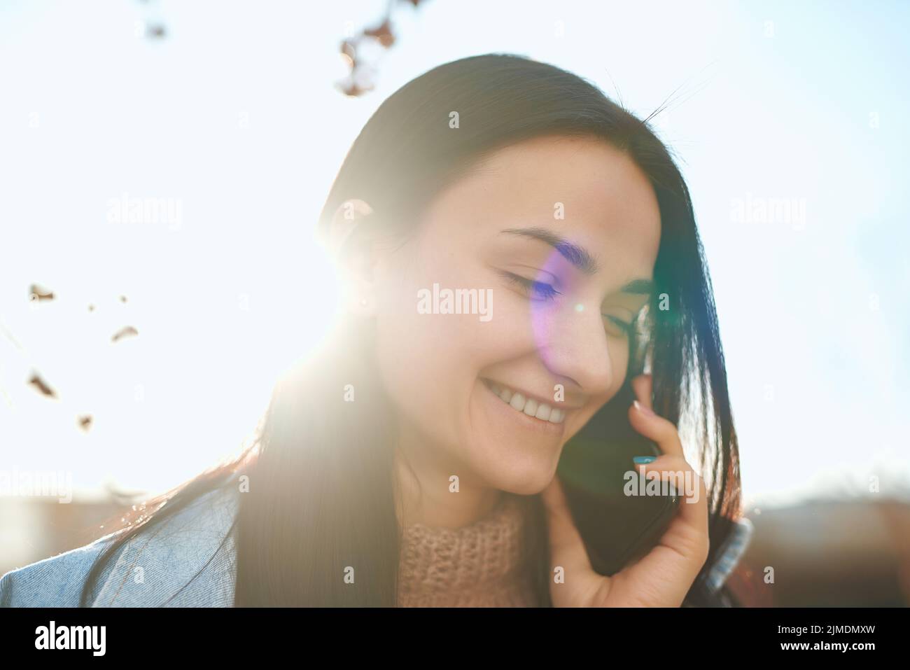 Attraente donna posa con un cellulare alla luce del sole d'autunno Foto Stock