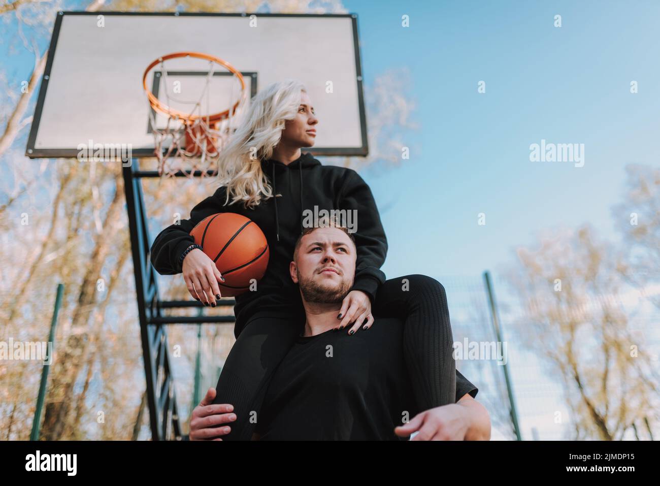 Giovane uomo e donna in posa sul campo da basket Foto Stock