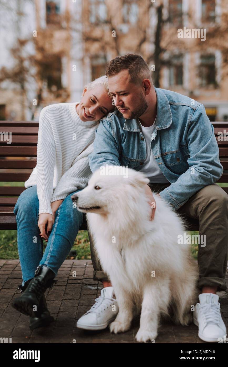 Coppia felice che ha riposato sulla panchina, prendendosi cura del loro cucciolo Foto Stock