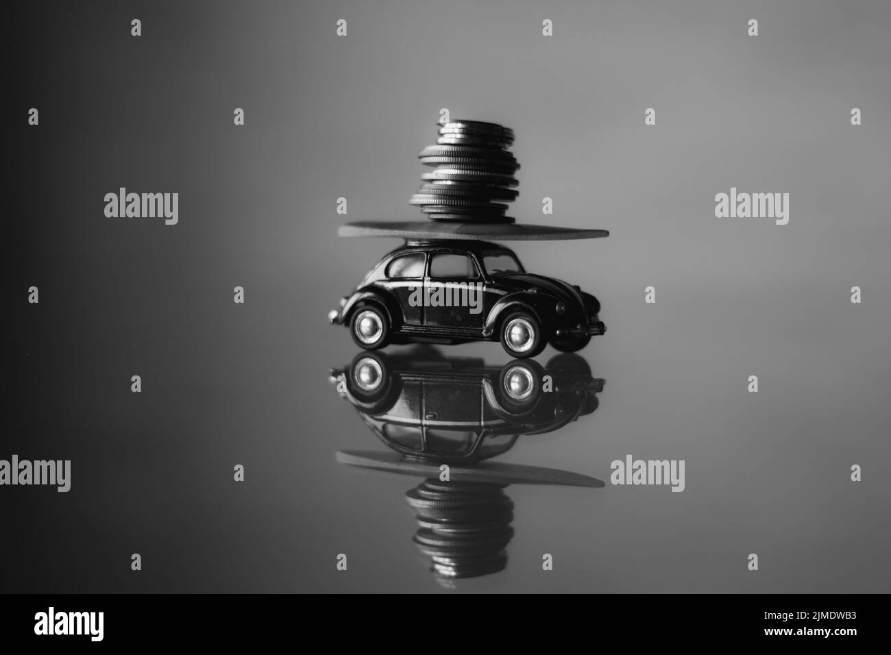 L'automobile piccola del giocattolo dei bambini trasporta una pila di soldi sul tavolo a casa, prestito dell'automobile, corsa Foto Stock