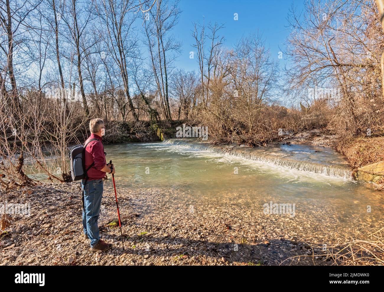 Escursionista di circa 60 anni, sulla riva del torrente. Foto Stock