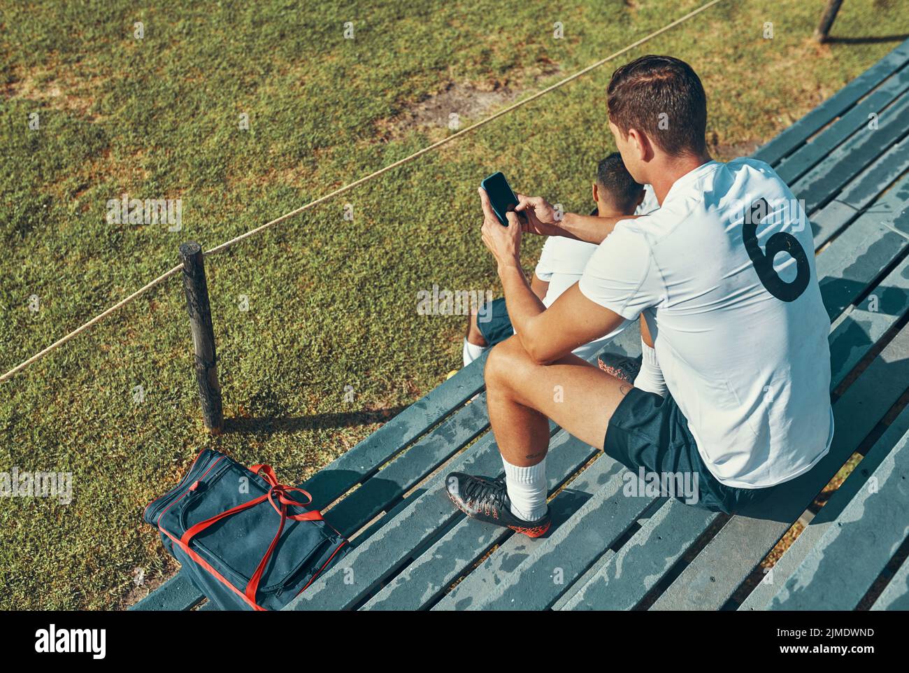 Perso il gioco recuperare online. Un giocatore di rugby che usa il suo cellulare mentre si siede sulla panchina. Foto Stock