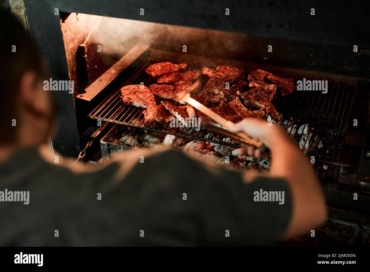 HES sui doveri di barbecco. Primo piano di un uomo irriconoscibile grigliare carne mentre si fa un barbecue. Foto Stock