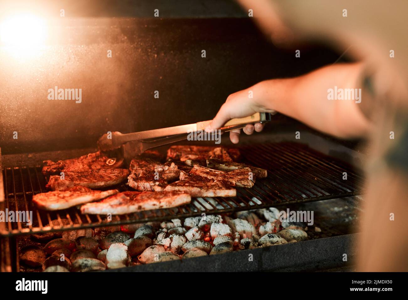 Esalta il sapore alla griglia. Primo piano di un uomo irriconoscibile grigliare carne mentre si fa un barbecue. Foto Stock