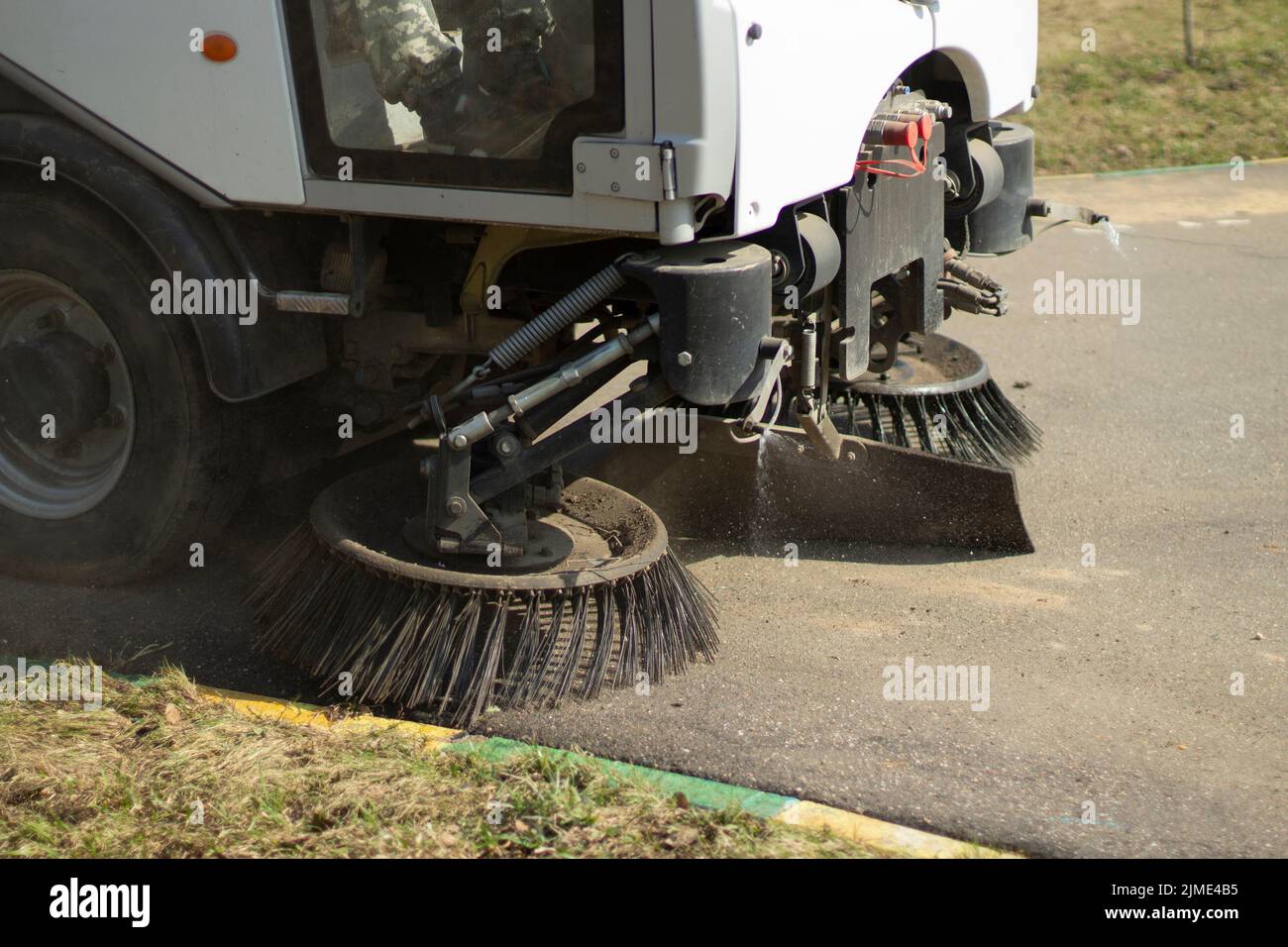 La spazzatrice sta spazzando l'asfalto. Pulire il percorso con un veicolo per la pulizia. Foto Stock