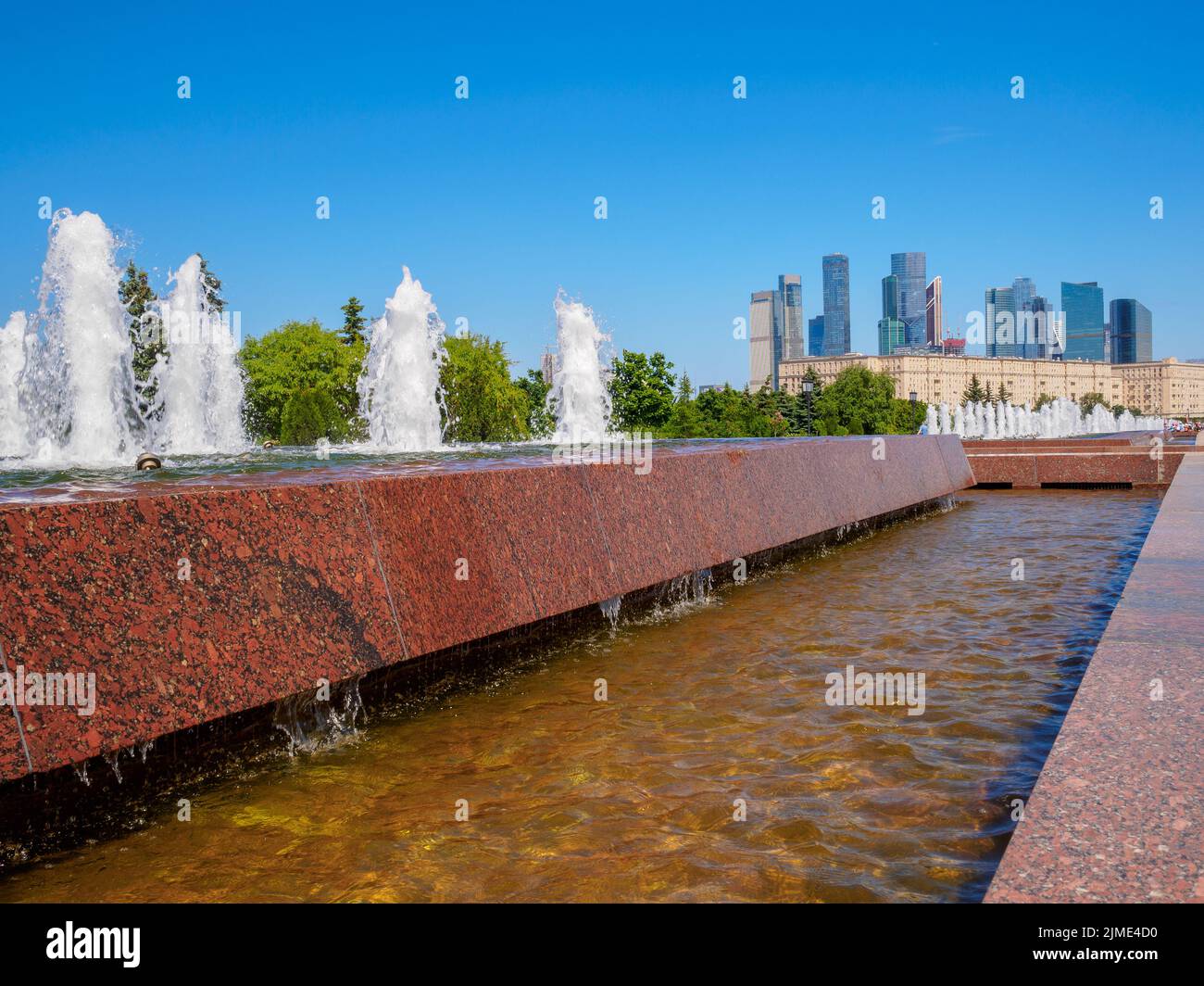 Getti di fontane sullo sfondo di grattacieli e un cielo blu senza nuvole. Foto Stock
