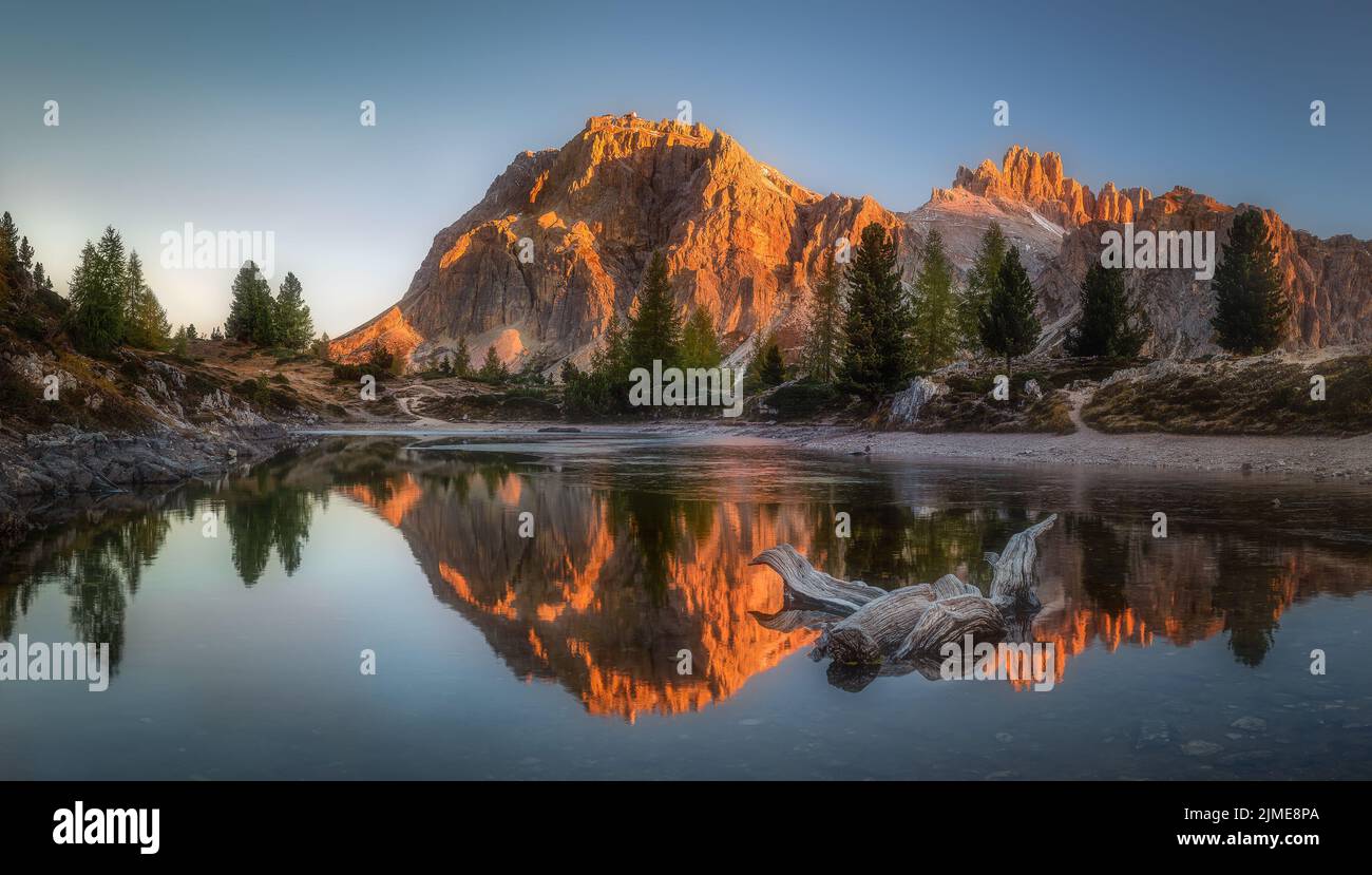 Un riflesso simmetrico di colline rocciose e alberi sul lago Limides Foto Stock