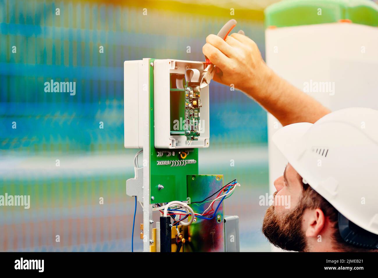 Un ingegnere elettrico qualificato crea un dispositivo di controllo e misurazione in un impianto industriale in una giornata estiva. Foto Stock