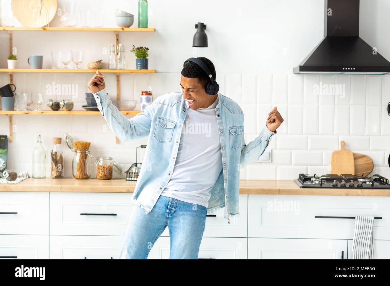 Felice libertà spensierata giovane uomo in cuffie ballare a casa in cucina da solo divertirsi Foto Stock