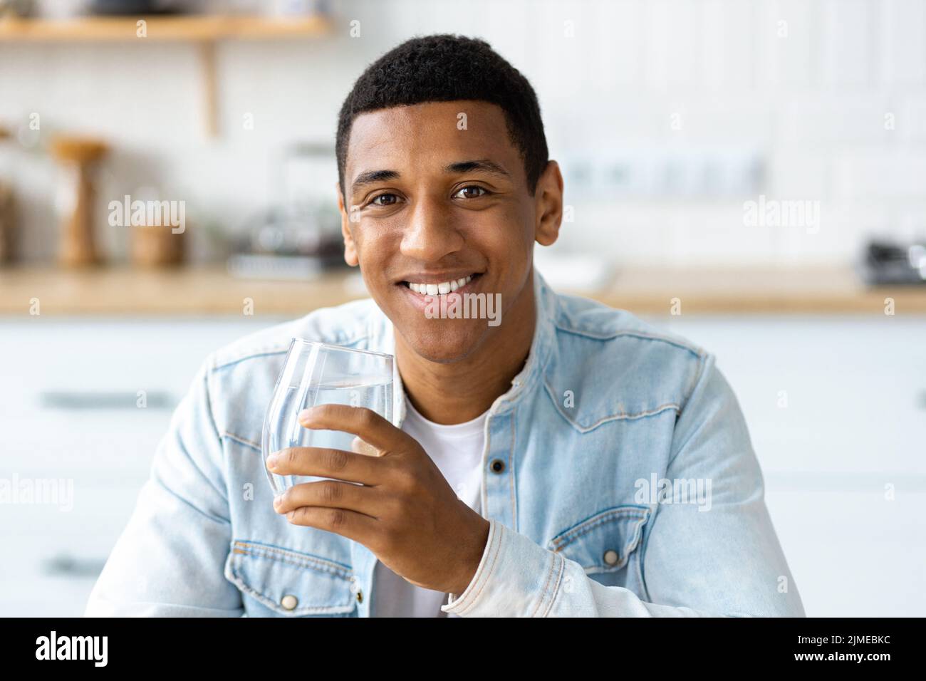 Stile di vita sano giovane uomo che tiene un bicchiere di acqua pulita fresca Foto Stock