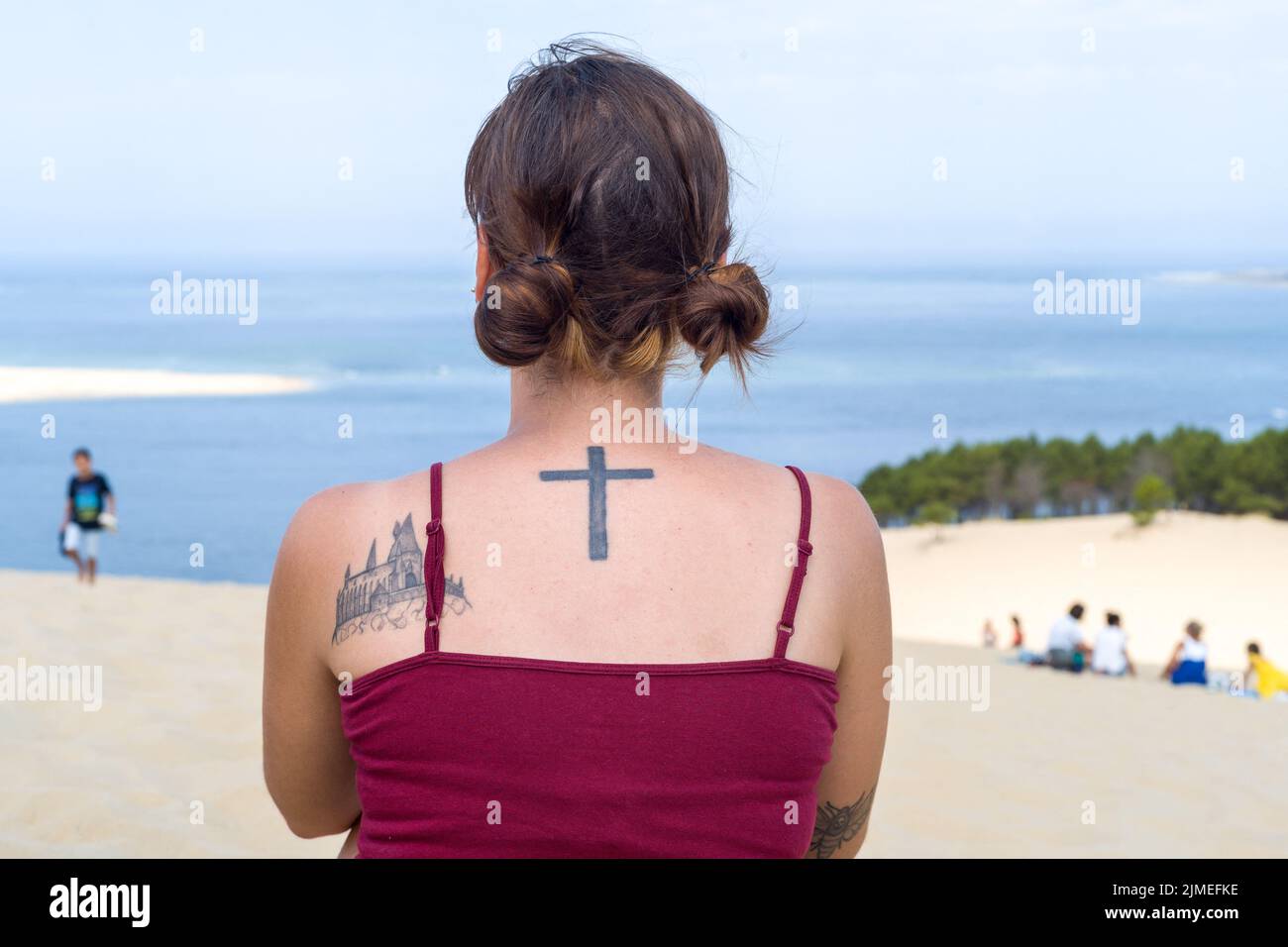 Una giovane donna con la schiena al laghetto, sulla Dune du Pilat, con due tatuaggi, uno raffigurante una croce nera e l'altro una chiesa, un'abbazia. Riapertura della Dune du Pilat e dei suoi turisti, dopo il fuoco. Francia, le-Pyla-sur-Mer, la teste-De-Buch. Agosto 4, 2022. Foto di Patricia Huchot-Boissier/ABACAPRESS.COM Foto Stock