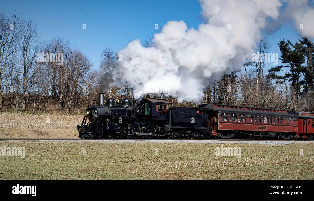 Antico treno a vapore restaurato soffiando fumo e vapore Foto Stock