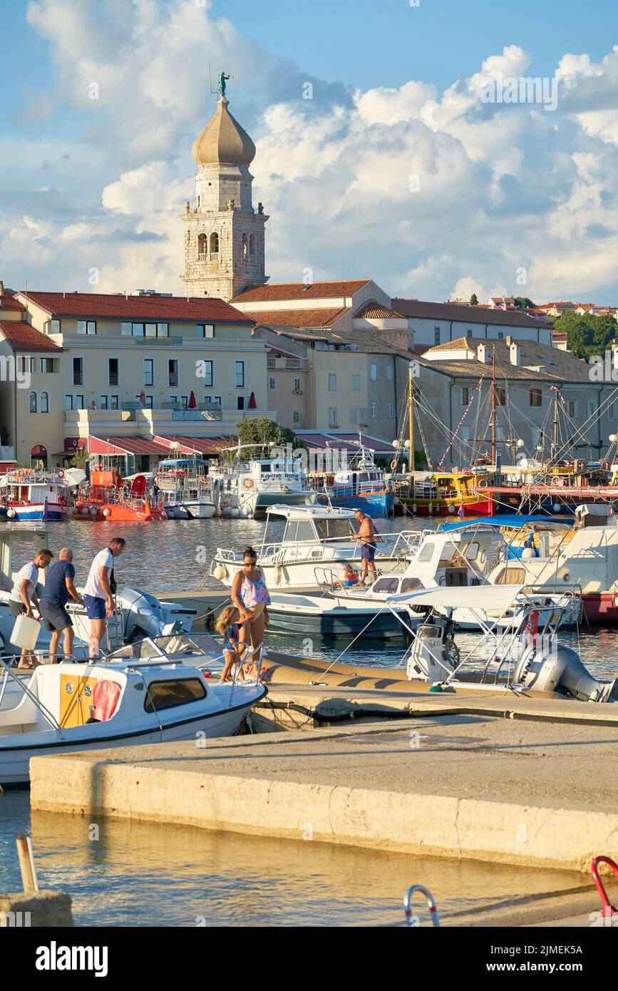 Vacanzieri nel porto di fronte alla città vecchia di Krk in Croazia Foto Stock