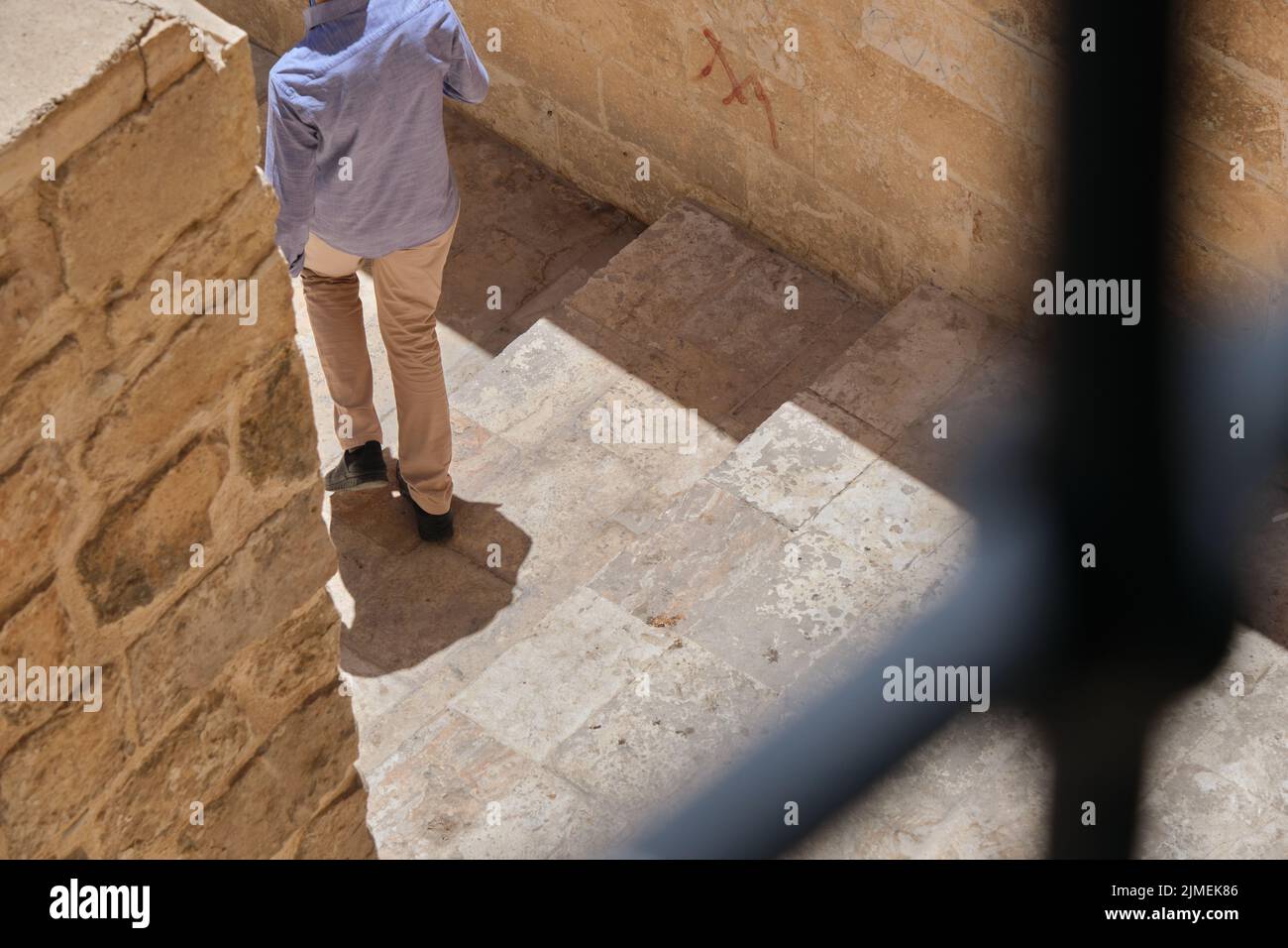 Uomo con una camicia bianca e un abito blu con uno zaino per strada a Mardin. Veduta aerea di un turista. Foto Stock