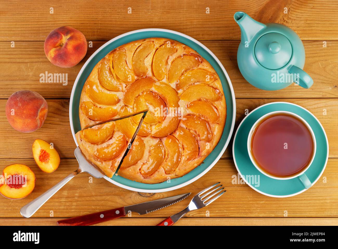 Torta fatta in casa con pesche e tazza di tè su tavola di legno. Vista dall'alto. Foto Stock