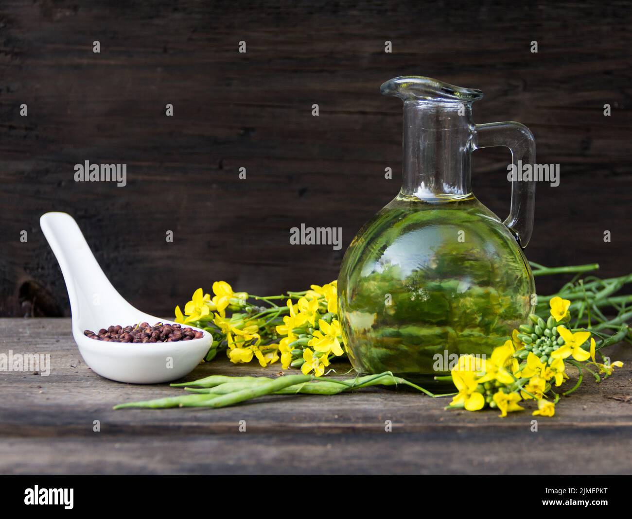 Olio di canola, fiori e semi su legno rustico Foto Stock Olio di canola, fiori e semi su legno rustico Foto Stock