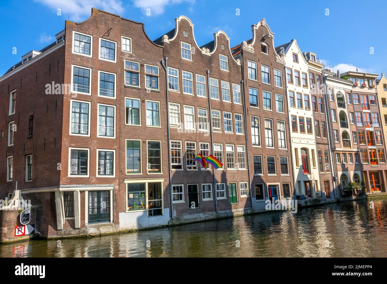 Le tradizionali case di Amsterdam sull'acqua e le bandiere LGBT Foto Stock