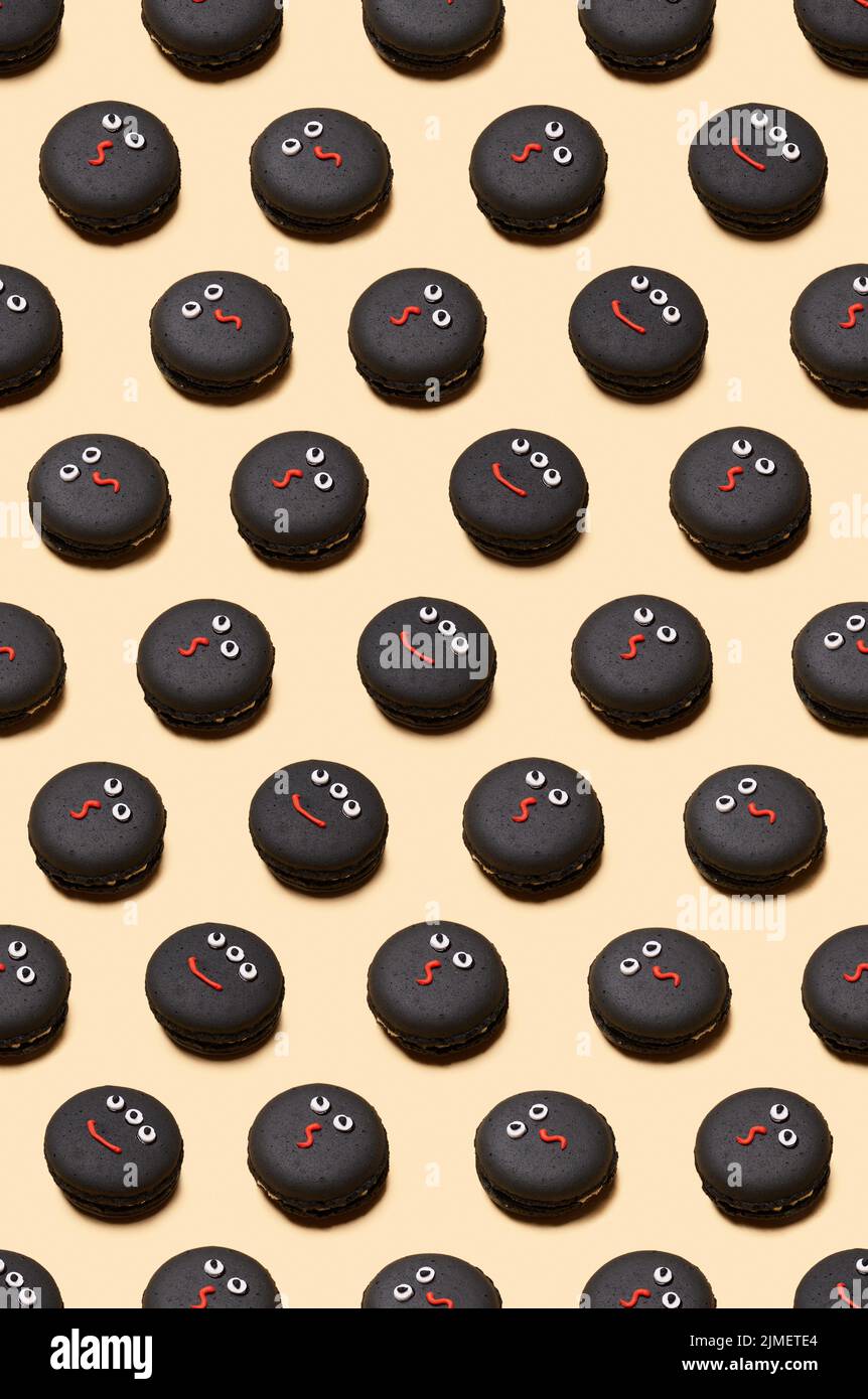 Motivo senza cuciture di Halloween Treat - facce di mostro decorate con macaron. Felice Halloween concetto Foto Stock