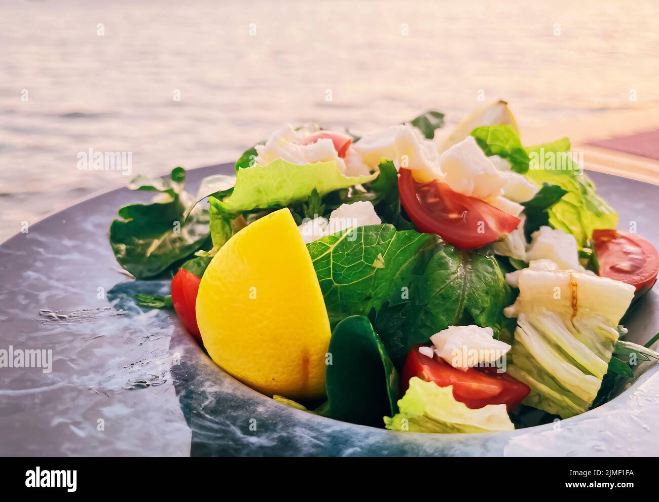 Dieta sana, cibo e cucina mediterranea concetto. Insalata con formaggio bianco e verdure fresche verdi su piatto in un ristorante Foto Stock