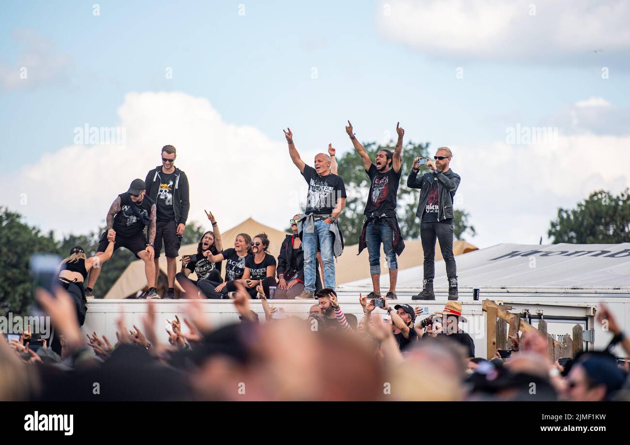 Wacken, Germania. 06th ago 2022. Gli amanti del festival cantano durante lo spettacolo della band Höhner al Wacken Open Air Festival. La band dialettale di Colonia si esibì per la prima volta a Wacken. Il WOA è considerato il più grande festival del metallo pesante del mondo. Credit: Daniel Reinhardt/dpa/Alamy Live News Foto Stock