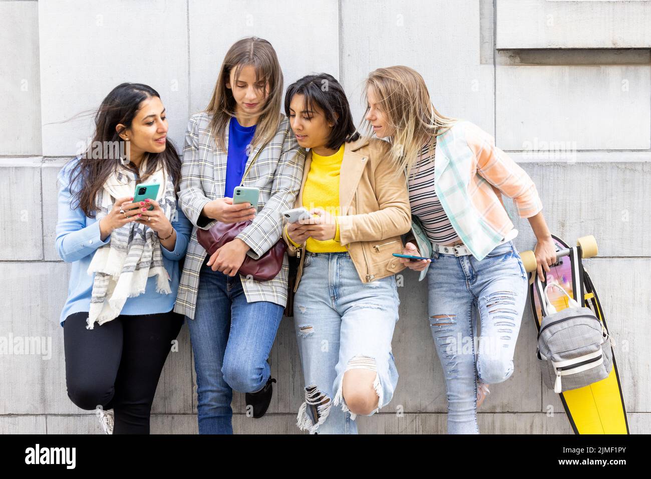 Il gruppo multirazziale di adolescenti si diverte a giocare felicemente con gli smartphone. Utilizzo da parte dei millennial di telefoni cellulari e applicazioni social Foto Stock