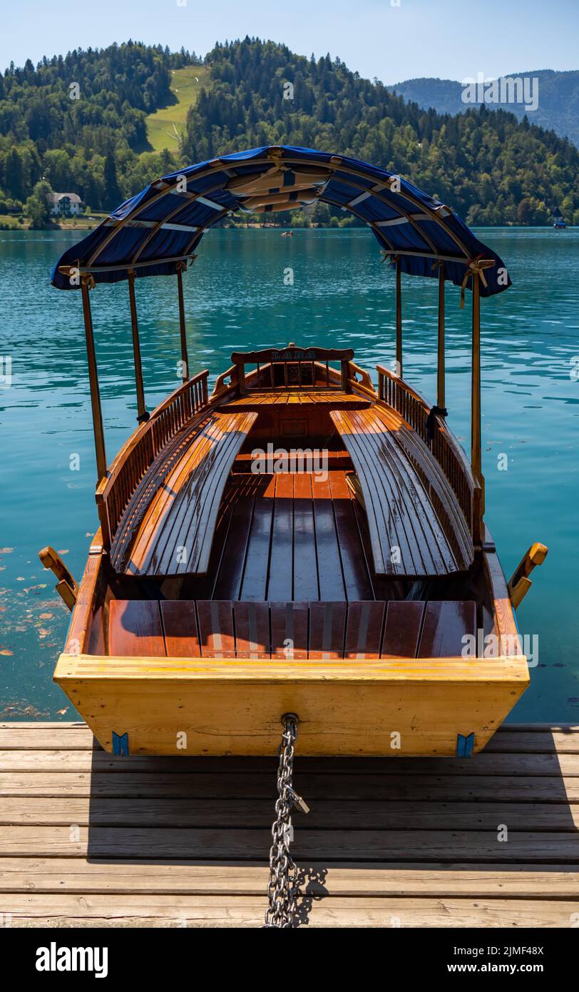 Una barca vuota da escursione sul lago di Bled vicino ad una collina con foresta. Bled, Slovenia Foto Stock