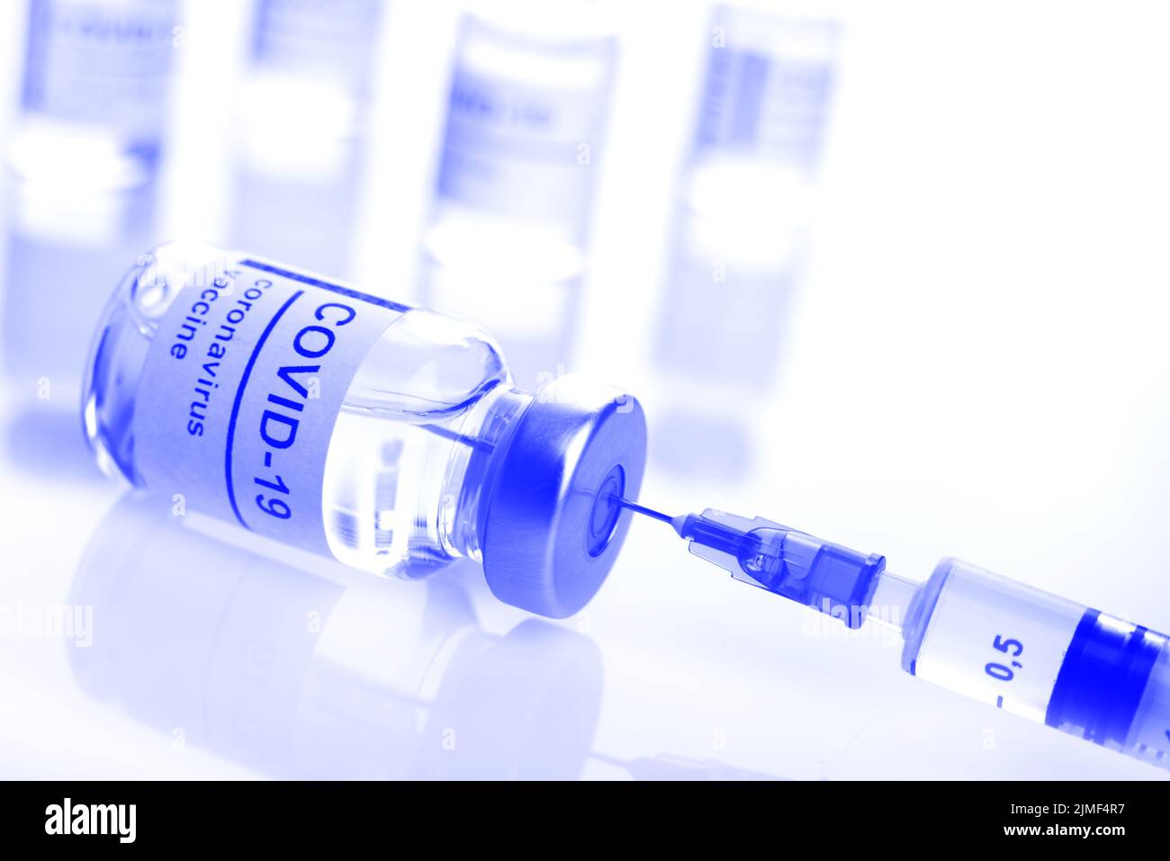 Flaconcino di vetro con etichetta di vaccino del coronavirus insieme alla siringa closeup, colore blu, foto Foto Stock