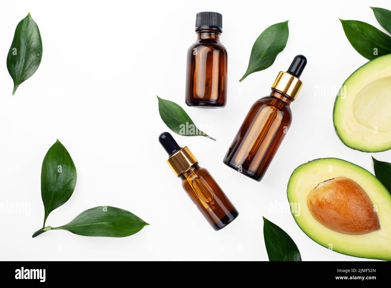 Flaconi contagocce con avocado fresco maturo e olio essenziale su tavola bianca piatta Foto Stock