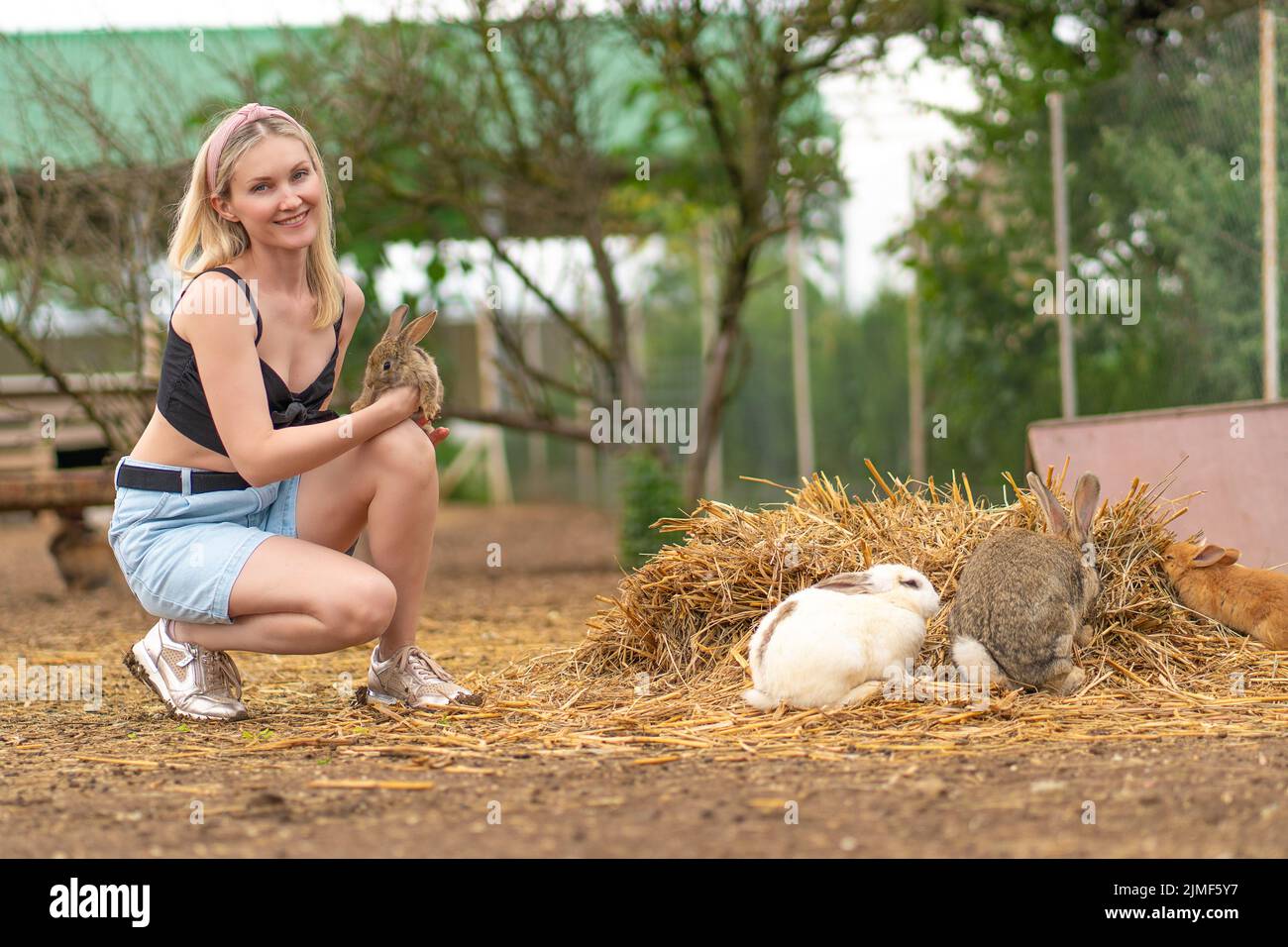 Ragazza prezzemolo nutre coniglio marrone coniglio pasquale coniglietto bianco sfondo giardino, da lepre giovane dal ritratto e dolce estate, orecchio animale. Divertente poco, Foto Stock