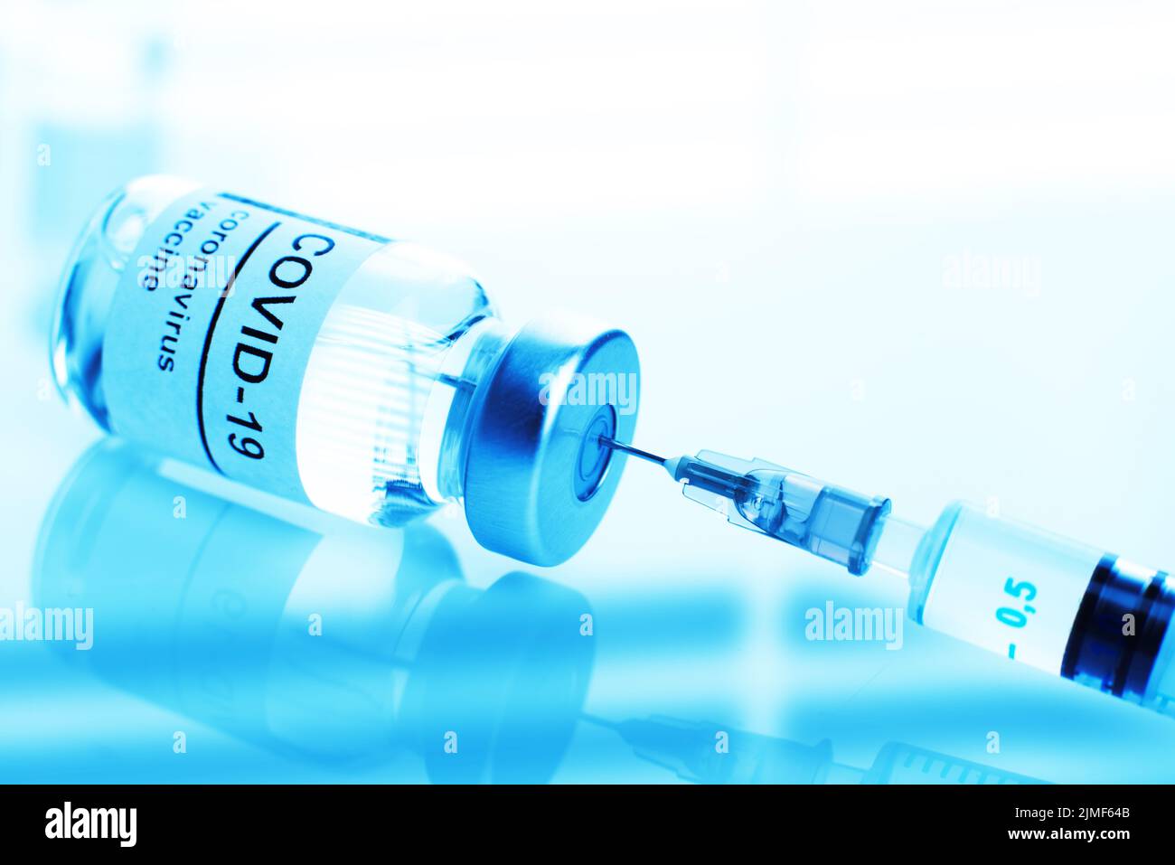 Flaconcino di vetro di colore blu con etichetta di vaccino contro il coronavirus e closeup della siringa Foto Stock