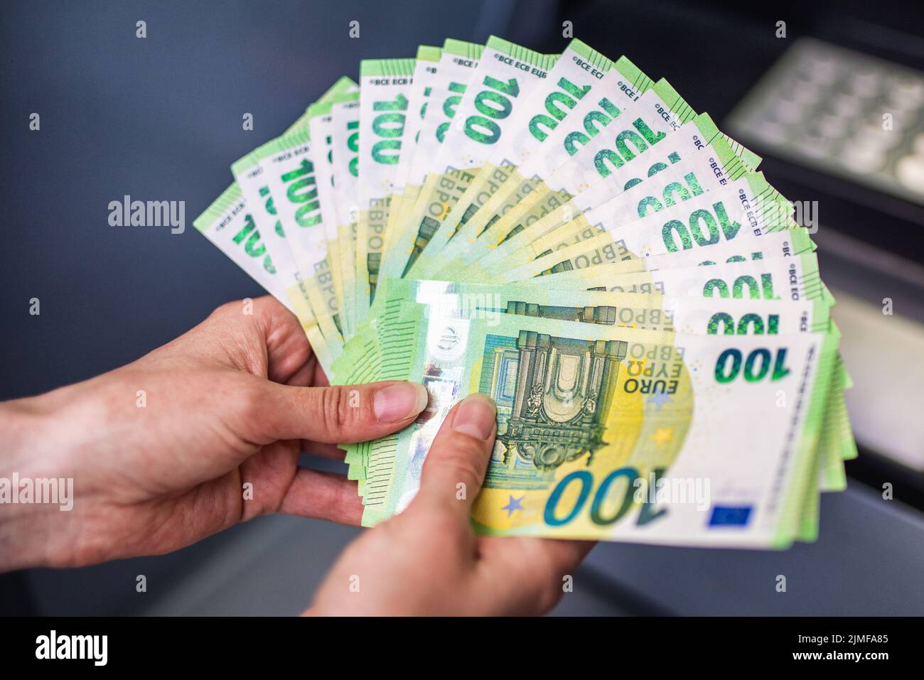 Un sacco di soldi in mano di una donna. Banconote in euro e bancomat in background. Concetto di denaro nelle mani Foto Stock