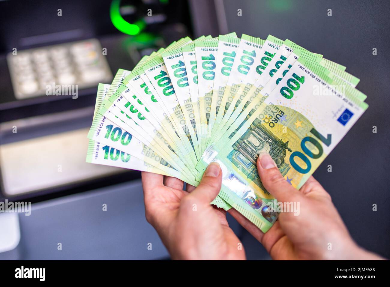 Un sacco di soldi in mano di una donna. Banconote in euro e bancomat in background. Soldi nelle mani Foto Stock