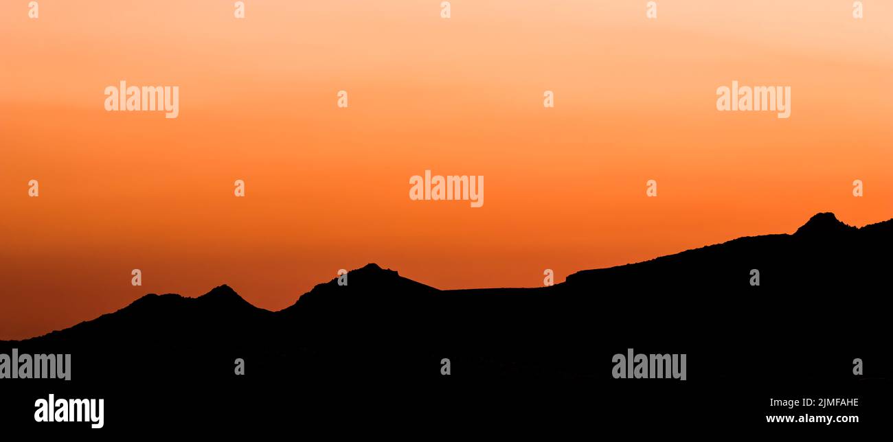 Sfondo da un bellissimo tramonto colorato con la silhouette delle montagne. Foto di alta qualità Foto Stock