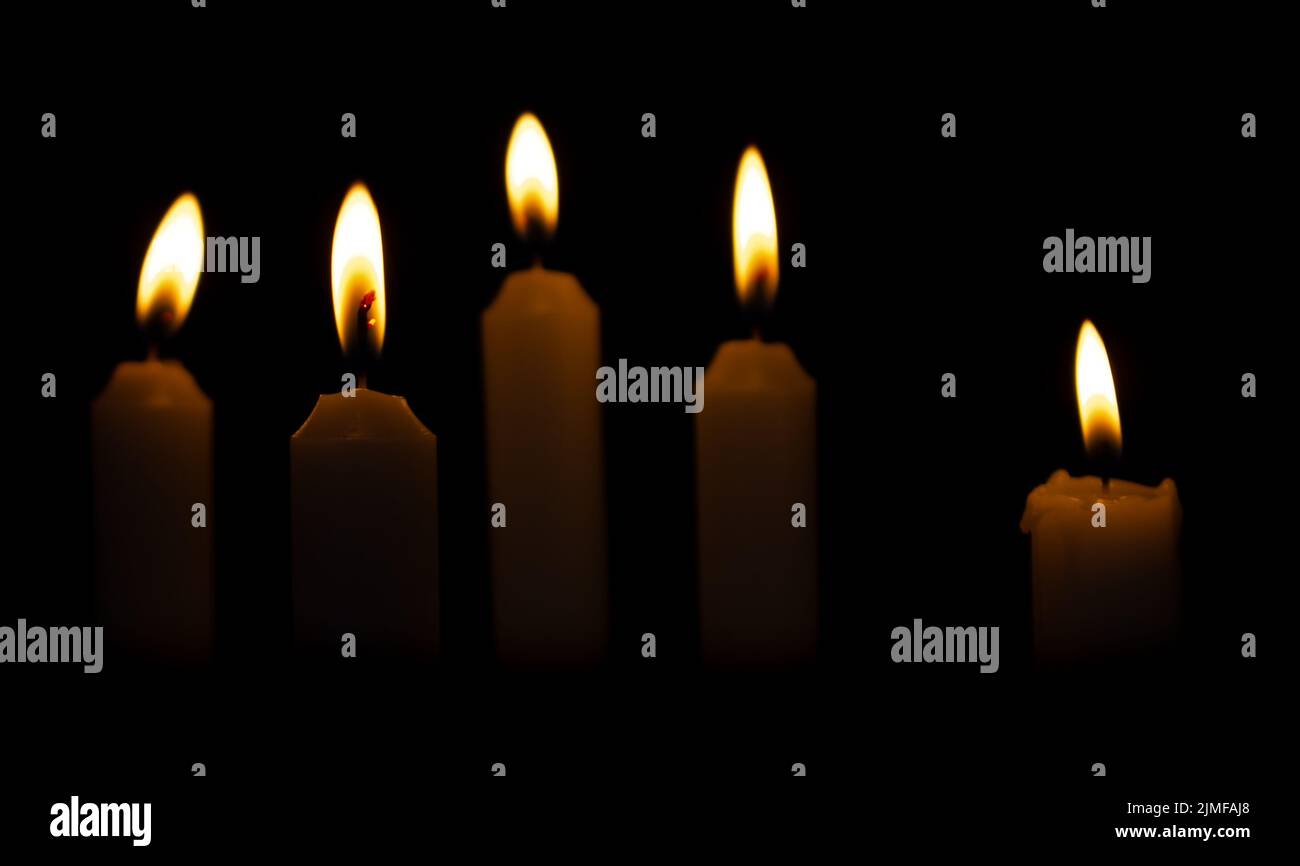 Cinque candele di Natale su uno sfondo scuro. Candele bruciate al buio Foto Stock