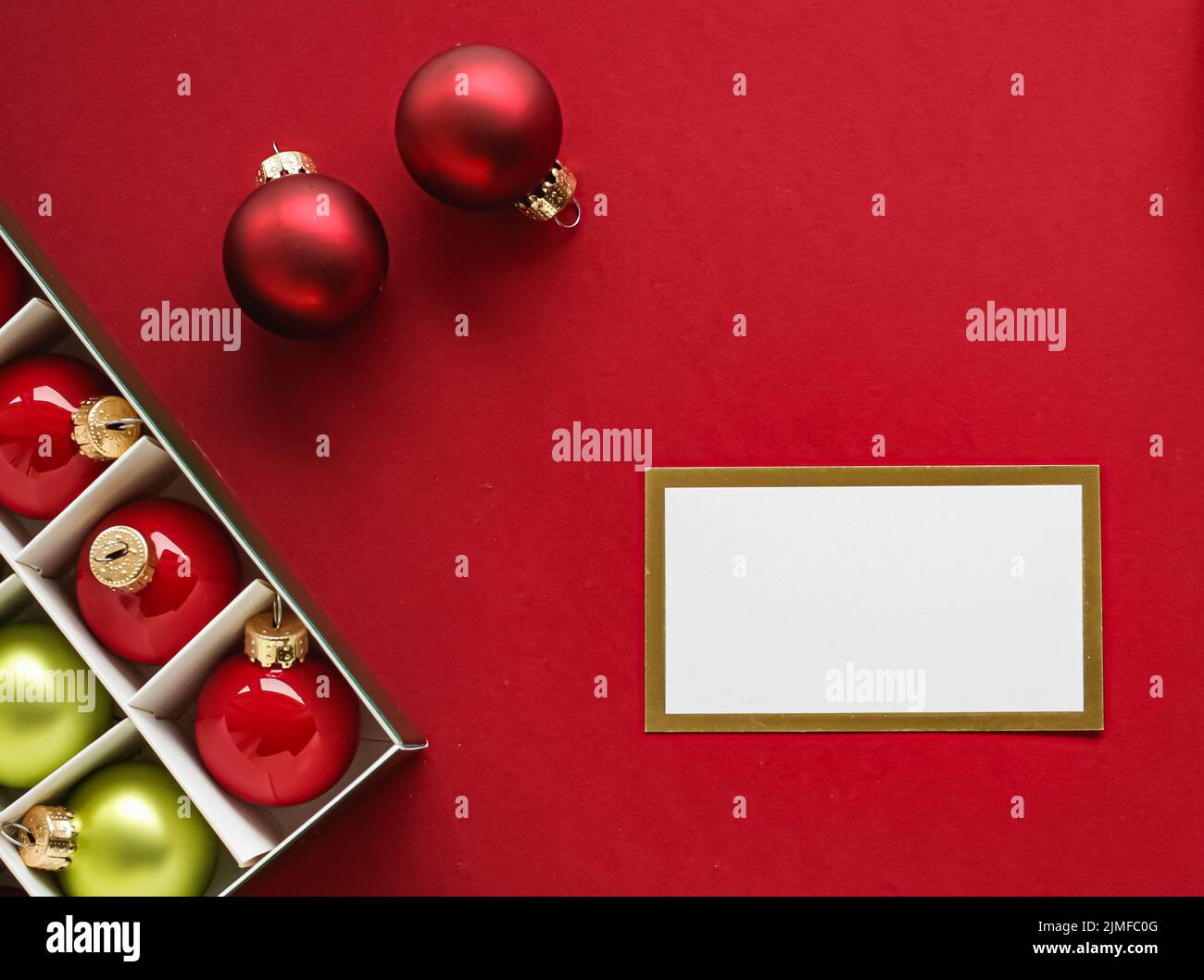 Design di identità del marchio di vacanza e concetto di flatlay di Natale. Biglietto da visita bianco e ornamento e decorazione di Natale su sfondo di carta rossa come Fla Foto Stock