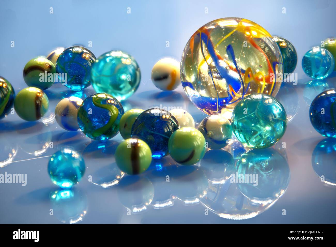 Pallottole in vetro di diverse dimensioni e colori con riflessi sullo sfondo blu Foto Stock