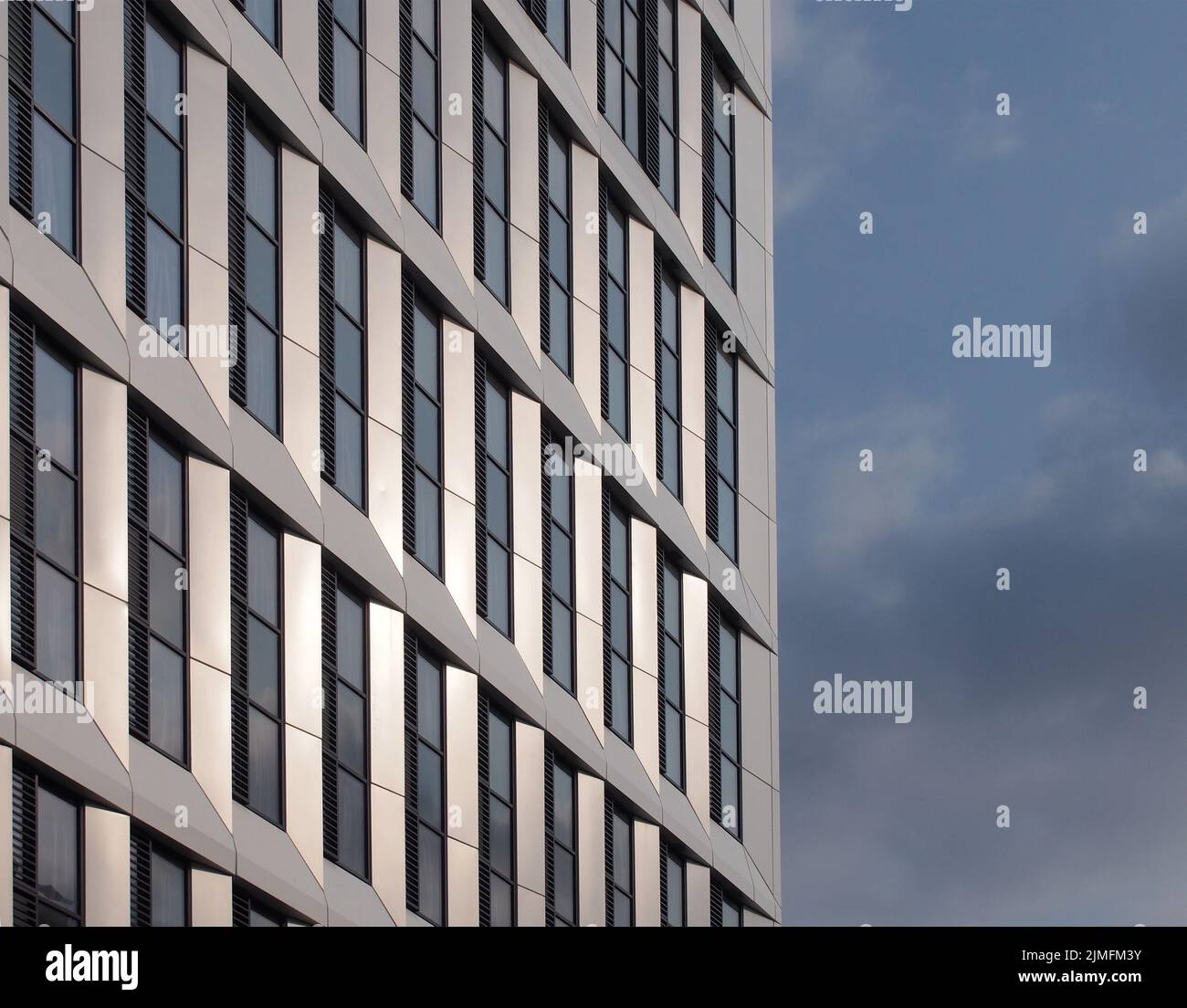 Primo piano dettaglio prospettico di un alto e moderno edificio di appartamenti con rivestimento metallico geometrico Foto Stock