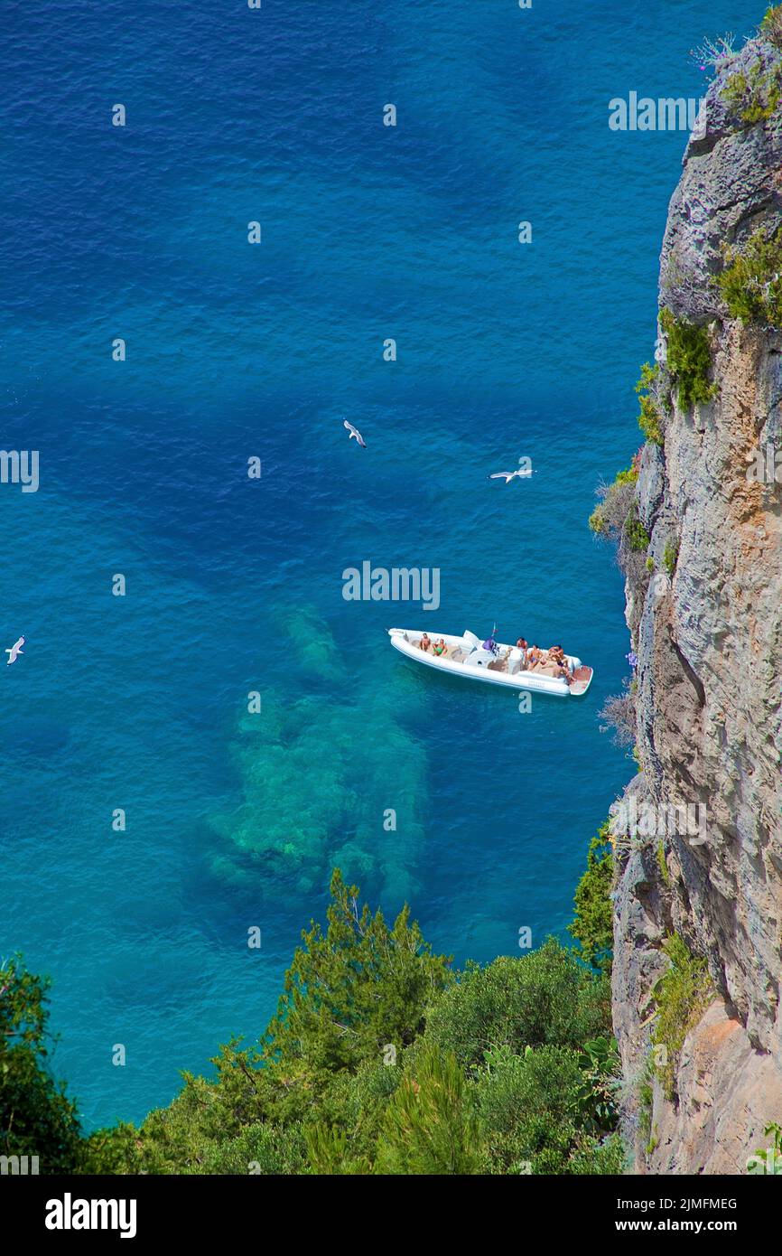 Villeggiante in uno zodiaco sulla costa ripida dell'isola di Capri, Golfo di Napoli, Campania, Italia, Europa Foto Stock