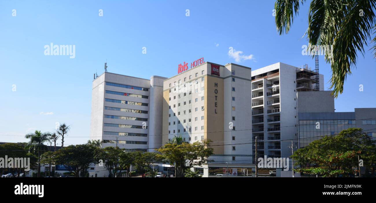 Facciata di un grande hotel internazionale, in una città all'interno del Brasile, Sud America, in primo piano, alberi, cielo blu sullo sfondo Foto Stock