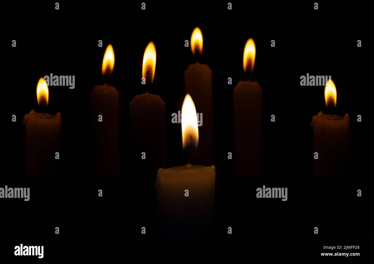 Candele bruciate al buio su sfondo nero. I riti religiosi, le feste o le sepolture sono accompagnati da candele accese. Foto Stock