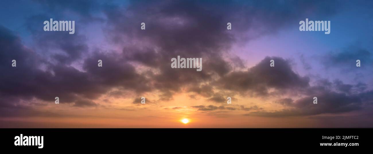 Astrazione panoramica dell'alba con sfondo sfocato di nuvole e cielo blu Foto Stock