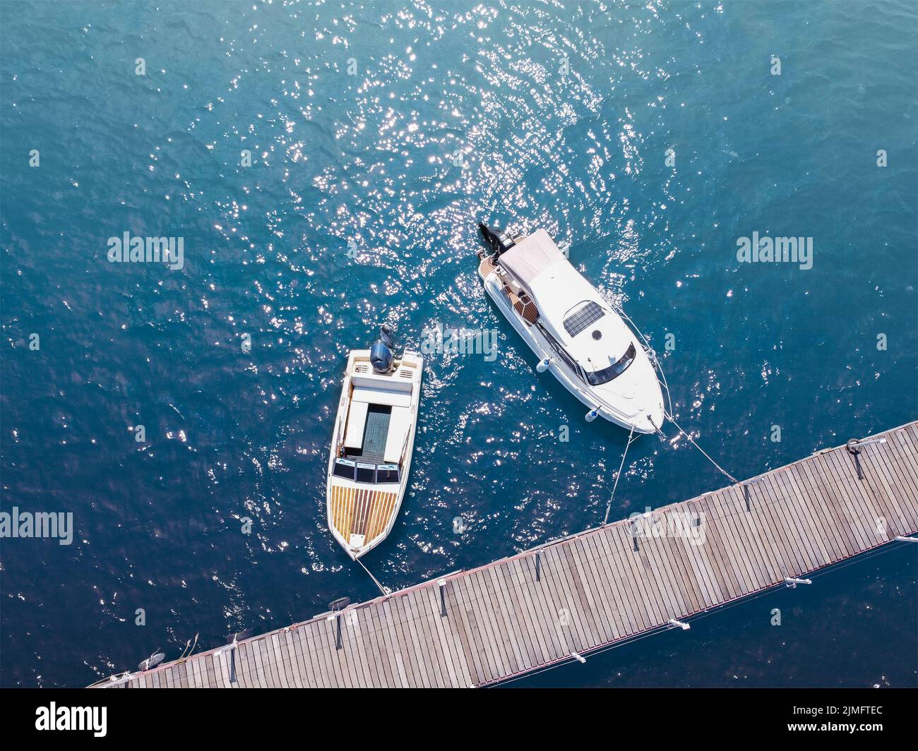 Barche vicino al molo sull'acqua. Acqua blu, mare e yacht Foto Stock