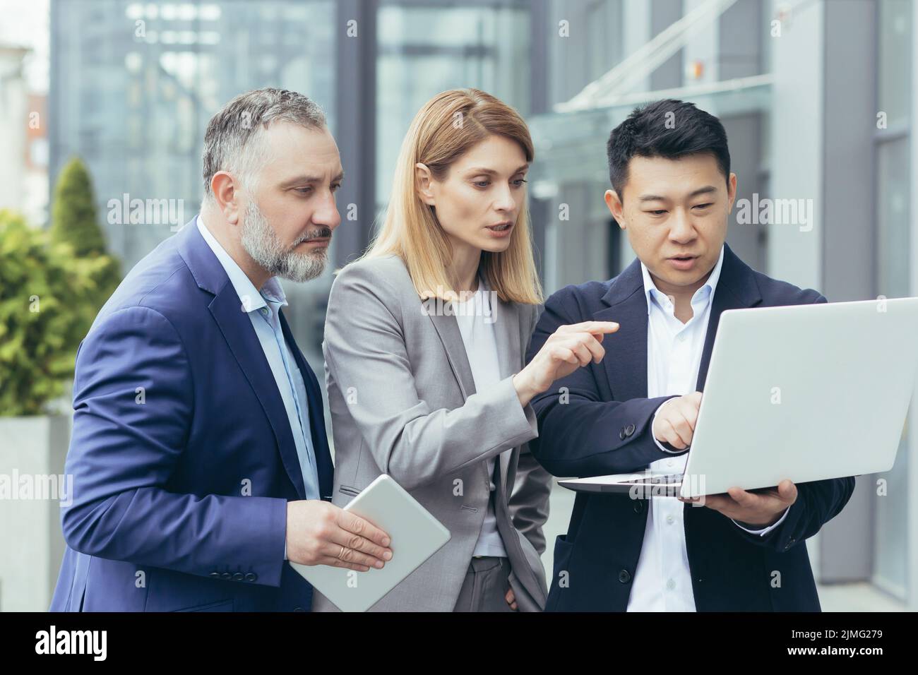 Gruppo diversificato di uomini e donne d'affari, insieme soluzioni di brainstorming fuori ufficio, team di colleghi che guardano lo schermo del notebook pensando alla strategia aziendale Foto Stock