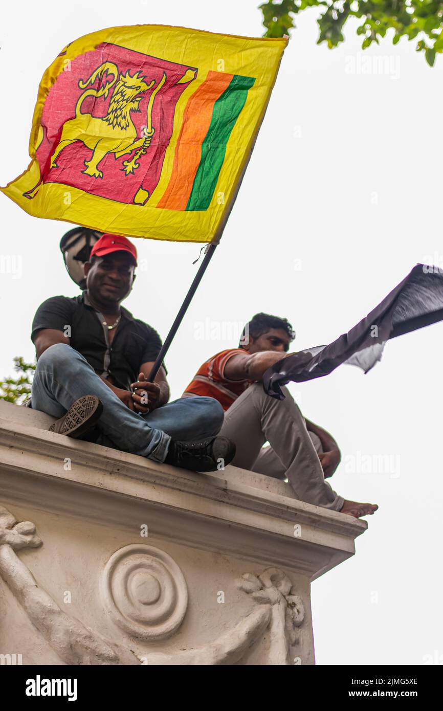 COLOMBO, SRI LANKA: 9th luglio 2022: Due manifestanti siedono in cima a un muro sulla via Chatham sventolando bandiera nazionale durante una protesta di massa contro la crisi economica. Foto Stock