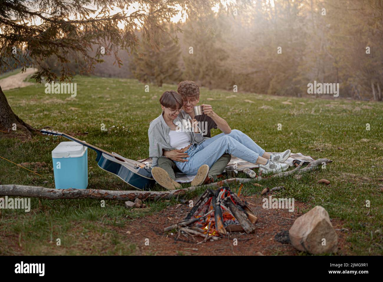 Felice giovane coppia di turisti seduti in abbraccio e ridere mentre si fa un picnic. Fine settimana. Foto Stock