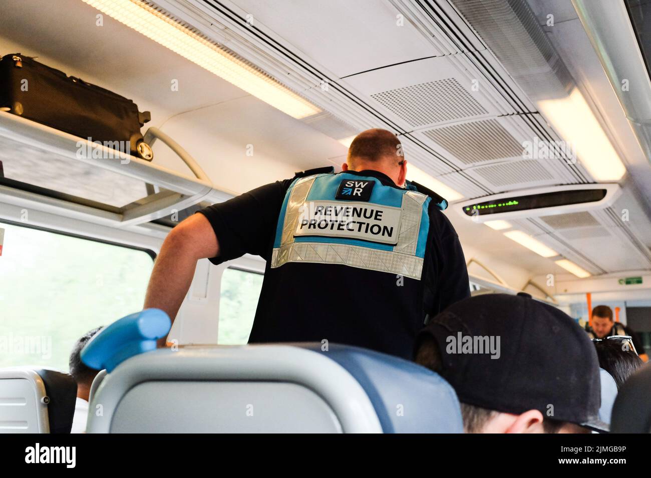 Un ufficiale di ispezione dei biglietti della ferrovia sud occidentale che passa attraverso un treno carrozza. Foto Stock