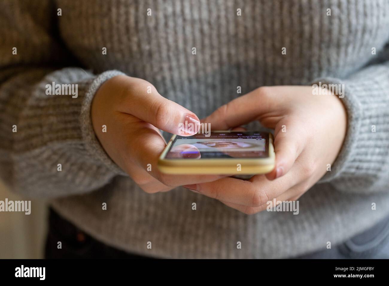 Primo piano di una giovane donna con smartphone, ragazza felice utilizzando il telefono cellulare in piedi. Concetto di dipendenza online, social media, Foto Stock