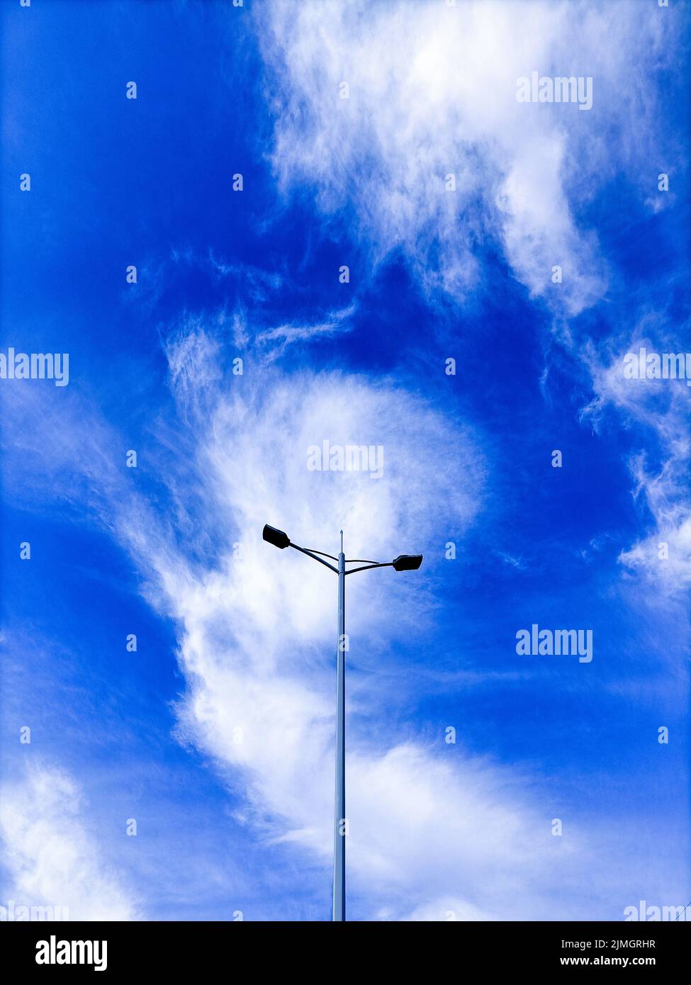 Un colpo verticale di palo di illuminazione contro sfondo cielo nuvoloso blu Foto Stock
